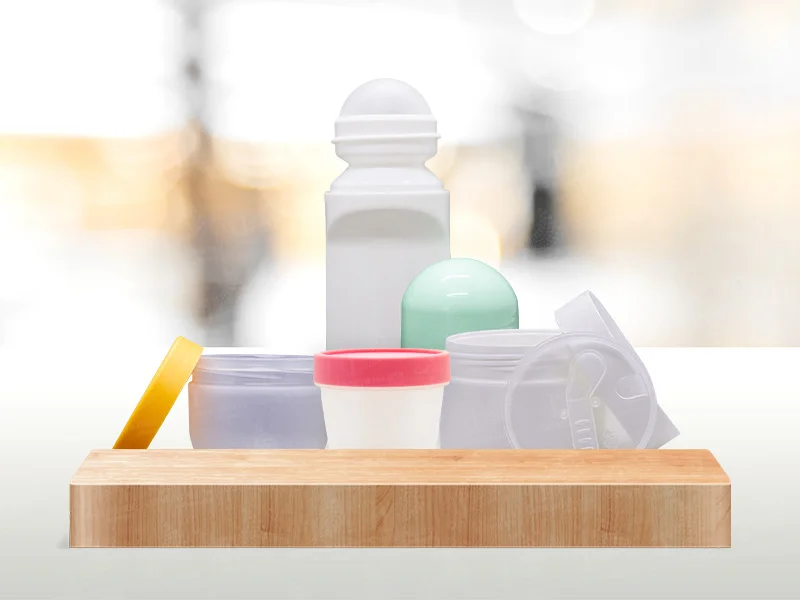 PP - Cahaya Jakarta Packaging Assorted medicine containers on a wooden tray, including a tall white bottle and small jars with colorful lids.